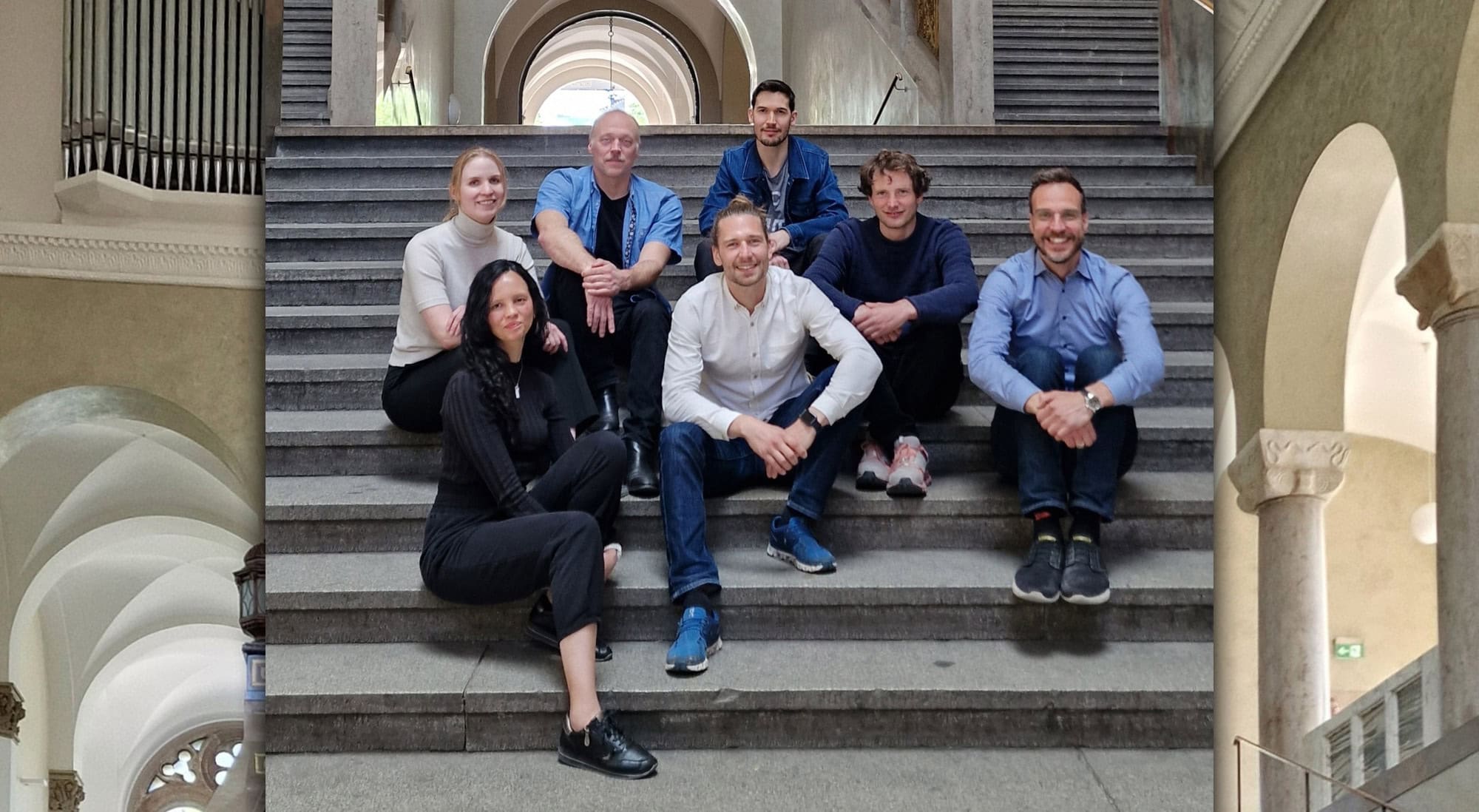 Das Team von Amplifold auf einer Treppe sitzend